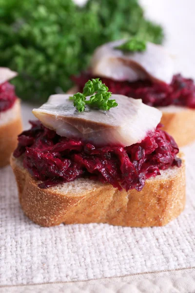 Rye toasts with herring and beets on tablecloth background — Stock Photo, Image