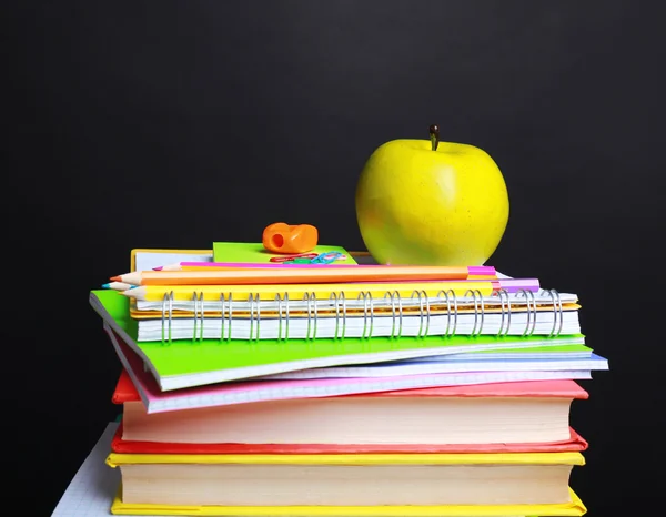 Schulbedarf und Apfel auf schwarzem Hintergrund — Stockfoto