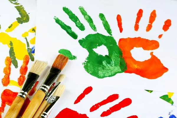 Hand prints of paint and brushes on white background — Stock Photo, Image