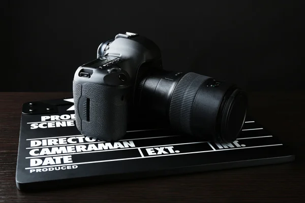 Photo camera and movie clapper on dark background — Stock Photo, Image