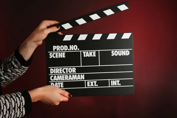Movie clapper in female hand on dark color background — Stock Photo, Image