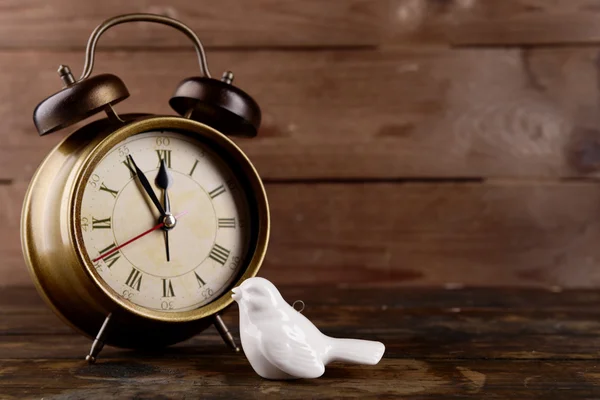 Horloge rétro avec oiseau décoratif sur table sur fond en bois — Photo