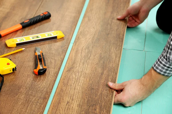 Trabalhador de carpinteiro instalando piso laminado na sala — Fotografia de Stock