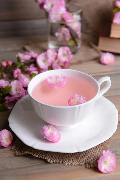 Beautiful fruit blossom with cup of tea on table on grey background — Stock Photo, Image