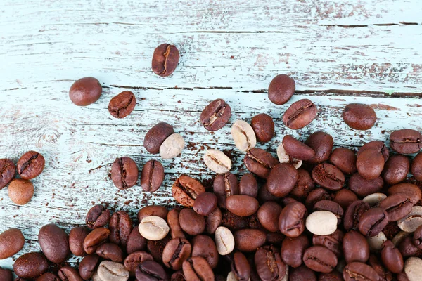 Kávová zrna na světle modré dřevěné pozadí — Stock fotografie