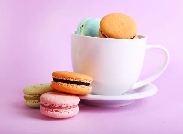 Assortimento di delicati macaron colorati in tazza colorata su sfondo a colori — Foto Stock