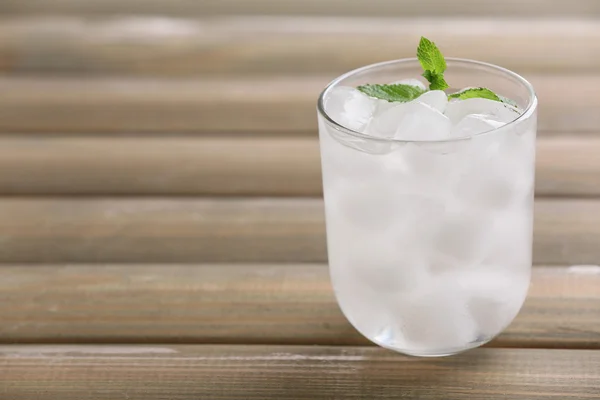 Glas met ijsblokjes op houten tafel — Stockfoto