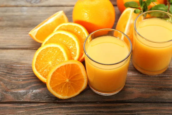 Copo de suco de laranja e fatias em fundo de mesa de madeira — Fotografia de Stock