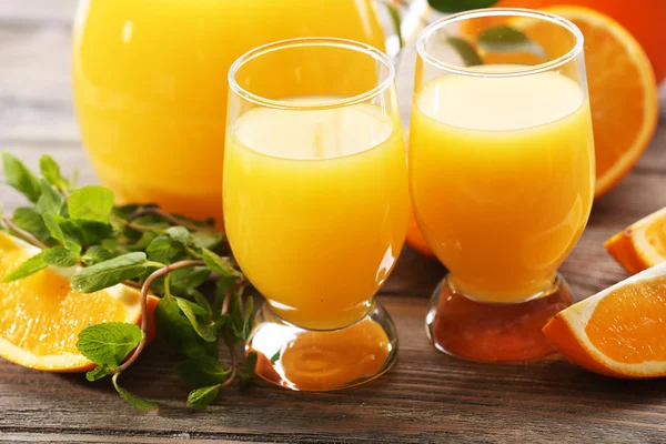 Copo de suco de laranja e fatias em fundo de mesa de madeira — Fotografia de Stock