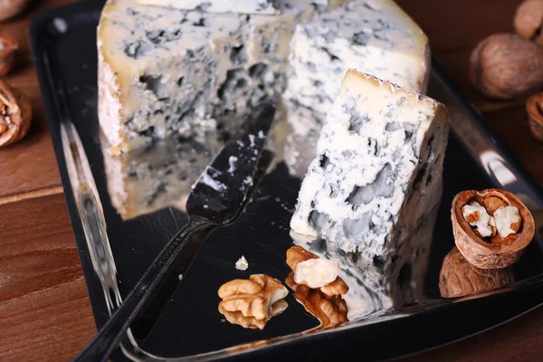 Blue cheese with nuts and blade on metal tray and wooden table background — Stock Photo, Image