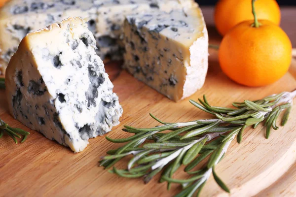 Queijo azul com raminhos de alecrim e laranjas a bordo e fundo de mesa de madeira — Fotografia de Stock