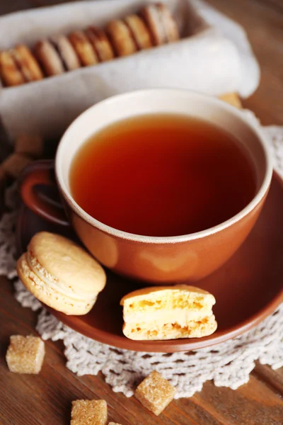 Bunte Makronen mit Tasse Tee auf hölzernem Hintergrund — Stockfoto