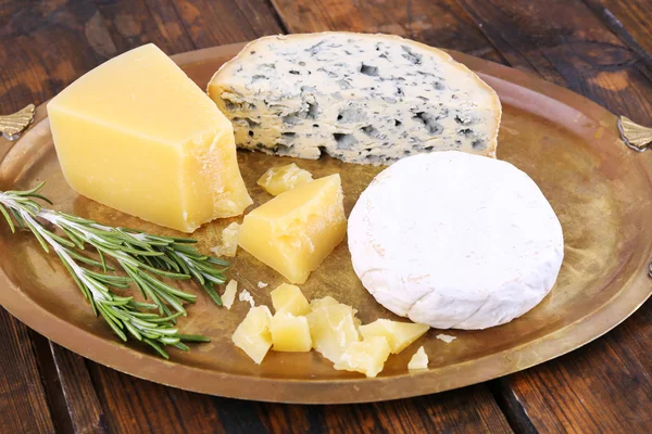Verschillende soorten kaas op metalen lade en houten tafel achtergrond — Stockfoto