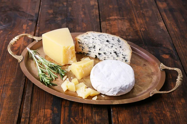 Diferentes tipos de queijo na bandeja de metal e mesa de madeira fundo — Fotografia de Stock