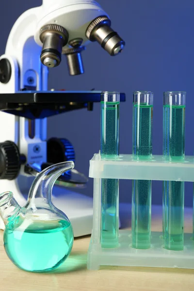 Microscope and test tubes on table, on color background — Stock Photo, Image