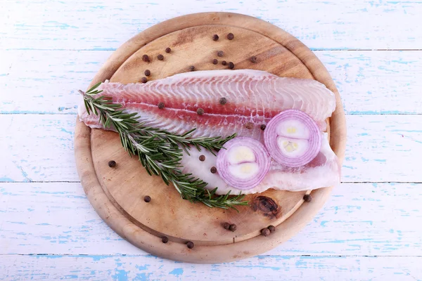 Pangasius fillet with herb and spices on cutting board and color wooden table background — Stock Photo, Image