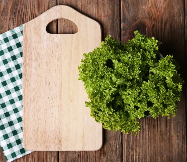 Cutting board with lettuce on wooden planks background — Stock Photo, Image