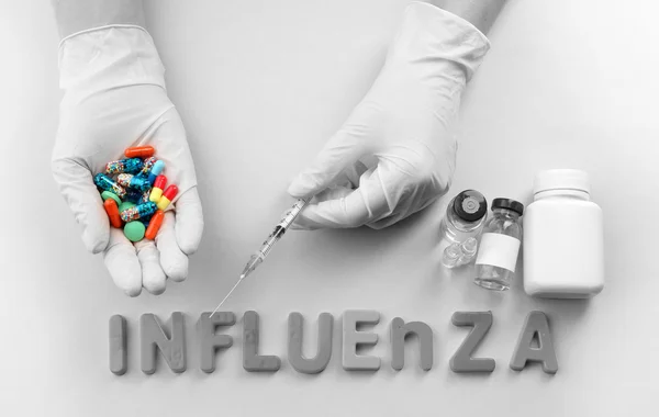 Mano humana de píldoras Medicamentos con palabra Influenza sobre fondo claro — Foto de Stock