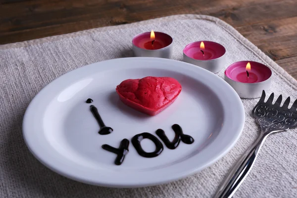 Galleta en forma de corazón en plato con inscripción I Love You, y velas sobre servilleta y fondo de mesa de madera —  Fotos de Stock