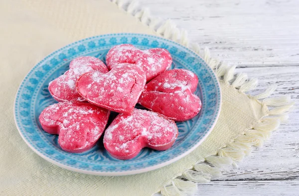 Biscotti in forma di cuore in piatto su sfondo tavolo di legno a colori — Foto Stock