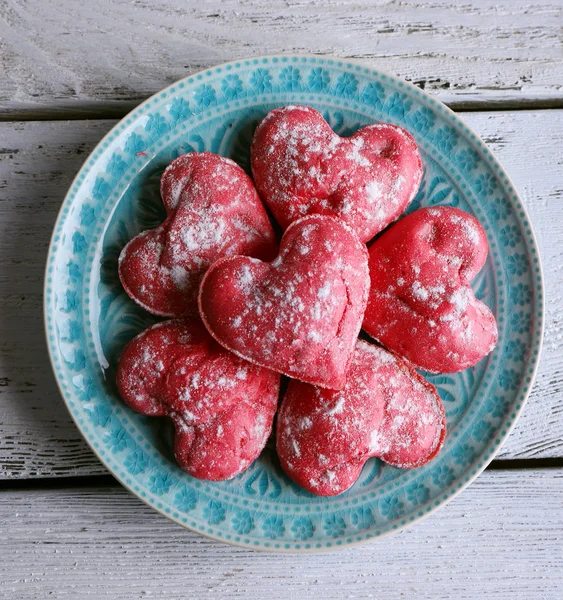 Biscotti in forma di cuore in piatto su sfondo tavolo di legno a colori — Foto Stock