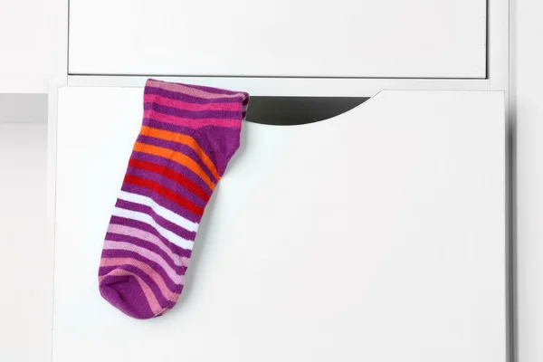 Stripped sock hanging on closet background — Stock Photo, Image