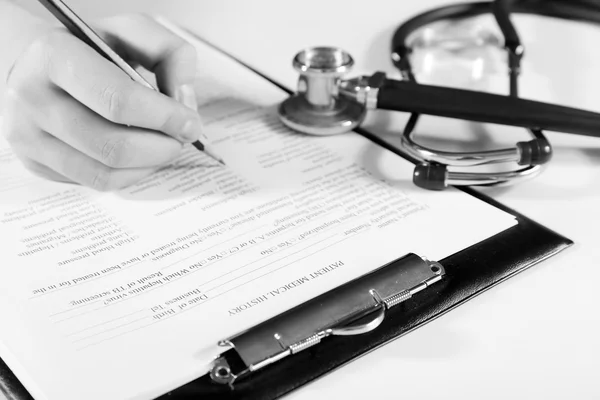 Mujer llenando historia médica en fondo claro —  Fotos de Stock