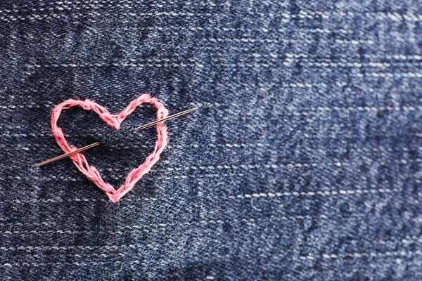 Jeans weefsel met roze hart geborduurd op, close-up — Stockfoto