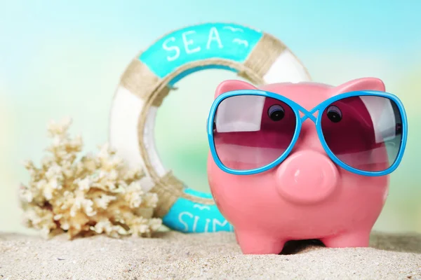 Piggy bank with sunglasses on the beach — Stock Photo, Image