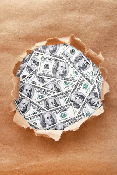 Dollar banknotes through torn  paper — Stock Photo, Image