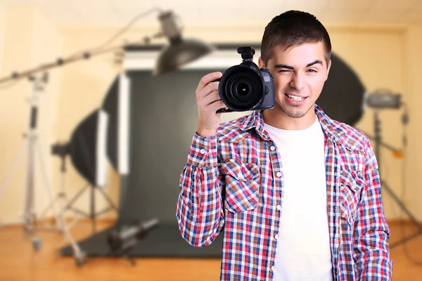 Fotógrafo guapo con cámara en estudio fotográfico — Foto de Stock