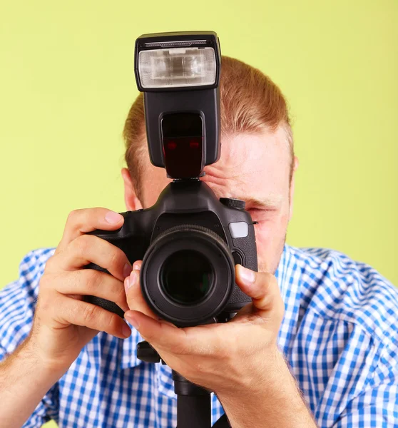 Schöner Fotograf mit Kamera auf Einbeinstativ, auf grünem Hintergrund — Stockfoto
