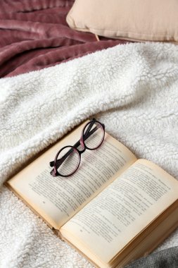 Kitap ve yatakta gözlük