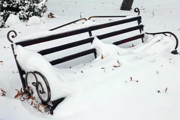 Bench in park with snowfall background — Stock Photo, Image