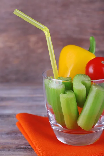 Bastoncini di sedano con peperone dolce e pomodoro ciliegia in vetro con tubo e tovagliolo su fondo rustico in legno — Foto Stock