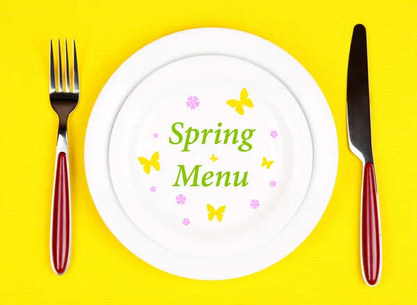 Teller mit Text "Frühlingsmenü", Gabel und Messer auf Tischdecken-Hintergrund — Stockfoto