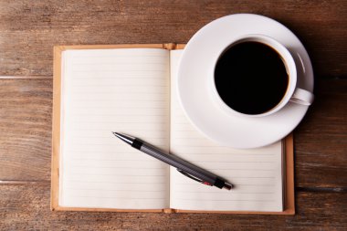 Fincan kahve üzerinde uçan daire ile defter ve kalem ahşap masa arka plan üzerinde