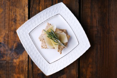 Parmesan peyniri dilimleri ince dal biberiye ahşap masa arka plan üzerinde plaka üzerinde ile ile Crispbread