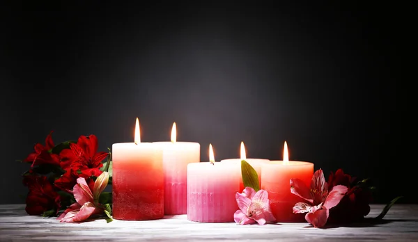 Piękne świece z kwiatami na drewnianym stole, na ciemnym tle — Zdjęcie stockowe