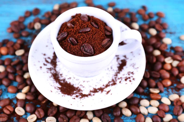 ถั่วกาแฟในถ้วยเซรามิคสีขาวพร้อมจานบนพื้นหลังไม้สีฟ้า — ภาพถ่ายสต็อก