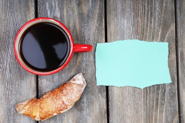 Composición de café, croissant fresco y tarjeta de papel sobre fondo de madera — Foto de Stock