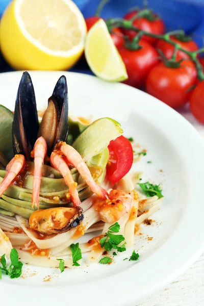 Tasty pasta with shrimps, mussels and tomatoes on plate on wooden background — Stock Photo, Image