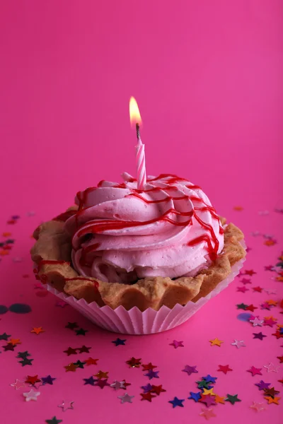 Bolo de xícara de aniversário com vela e estrelas coloridas no fundo rosa — Fotografia de Stock