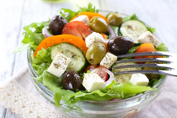 Salada grega em prato de vidro em guardanapo e cor de fundo de madeira — Fotografia de Stock