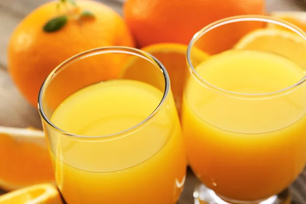 Copo de suco de laranja e fatias em fundo de mesa de madeira — Fotografia de Stock