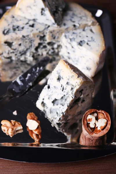 Blue cheese with nuts and blade on metal tray and wooden table background — Stock Photo, Image