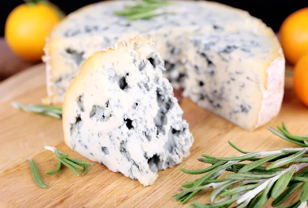 Queijo azul com raminhos de alecrim e laranjas a bordo e fundo de mesa de madeira — Fotografia de Stock