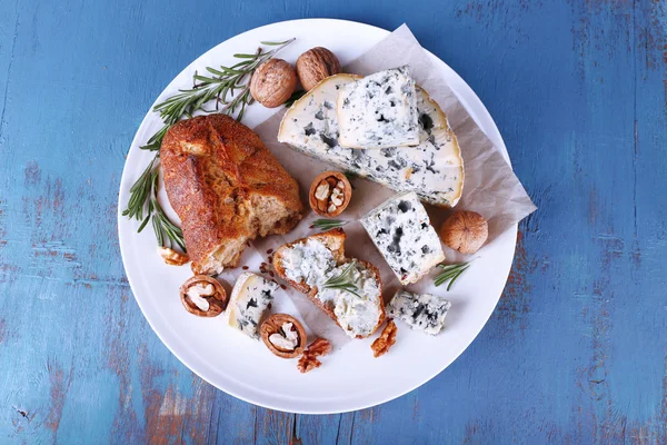 Blauwe kaas met takjes rozemarijn, brood en noten op plaat en kleur houten tafel achtergrond — Stockfoto