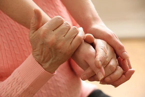 Vecchi e giovani che si tengono per mano su sfondo chiaro, primo piano — Foto Stock