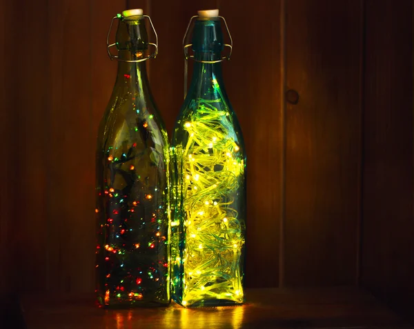 Різдвяні вогні в пляшках на дерев'яному фоні — стокове фото